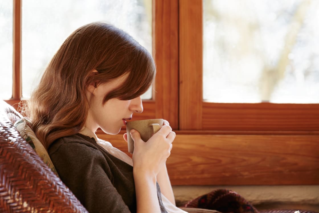 Woman Drinking Tea On Porch Of Log Cabin مجلة نقطة العلمية