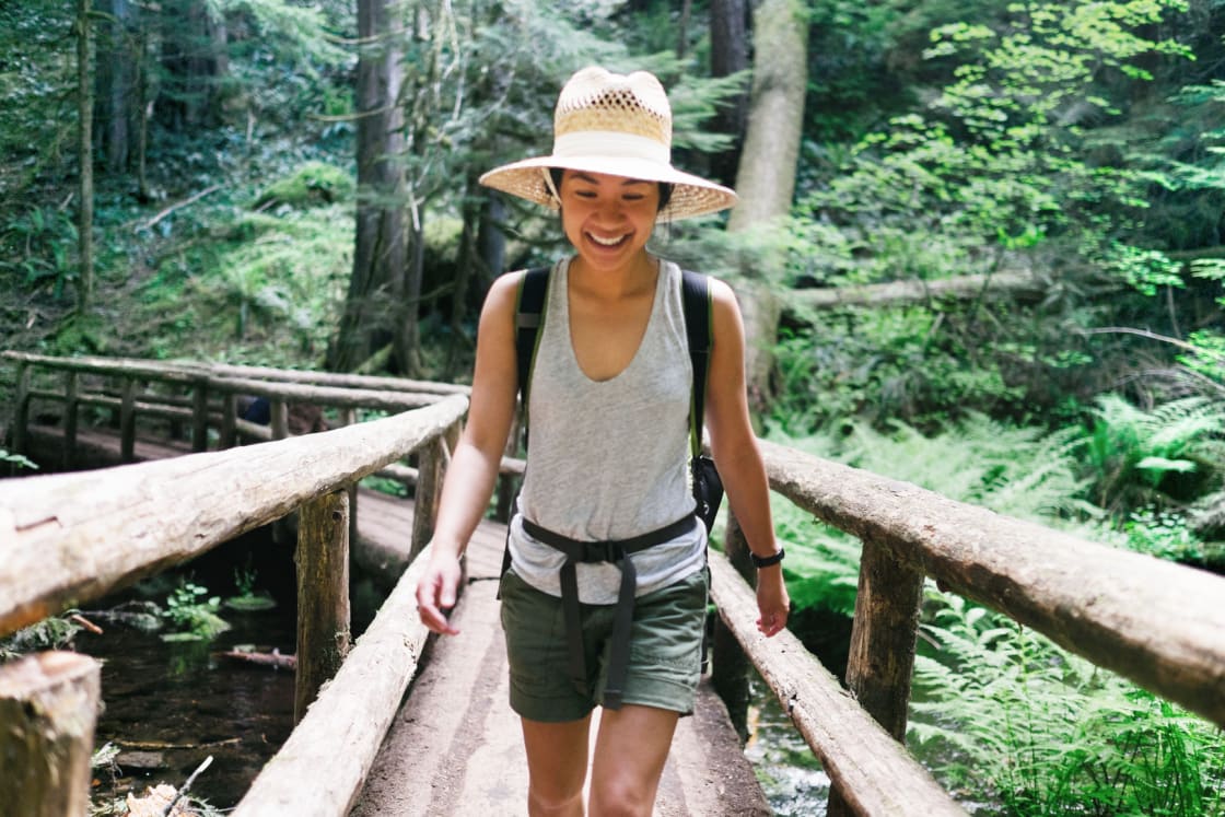 Woman Smiling While Crossing A Bridge On A Hike مجلة نقطة العلمية