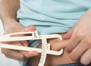 Man Measuring Belly Fat Calipers مجلة نقطة العلمية